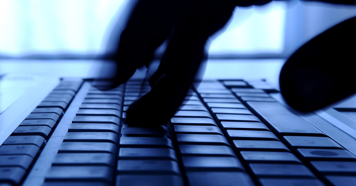 Close up of fingers typing on a keyboard in ominous lighting