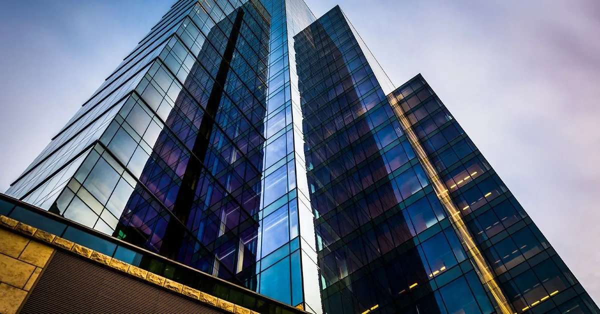 Modern commercial glass building view towards the sky.