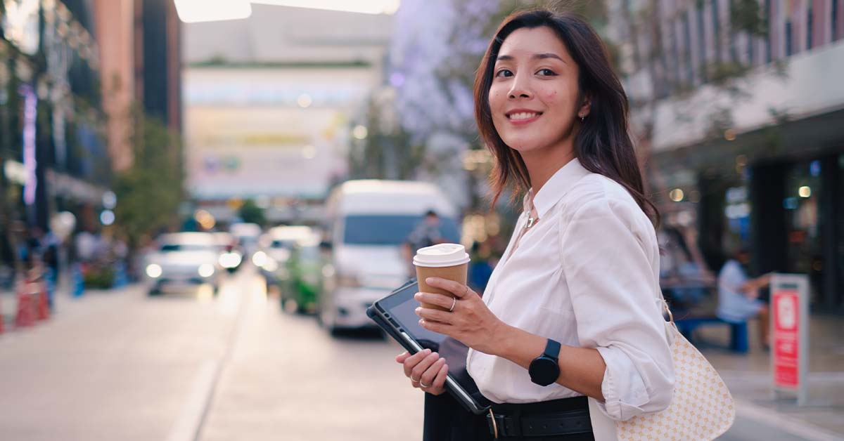 Image Young female businesswoman walks along downtown street with confidence.