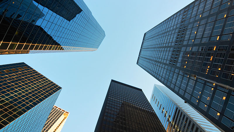 Image Glass commercial buildings frame a clear blue sky.