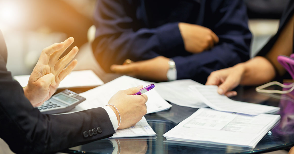 Image Closing agent meets with a couple over a table littered with documents