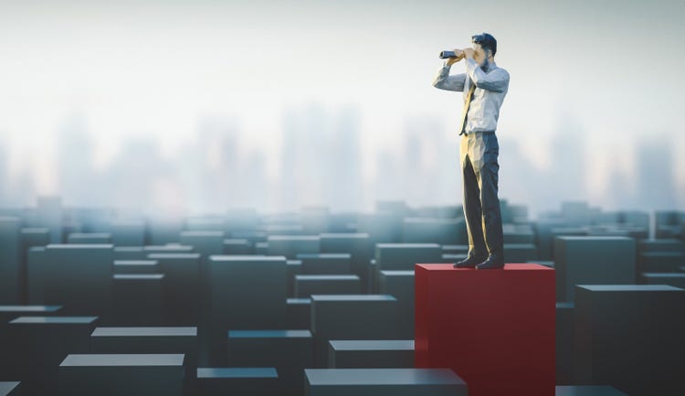 Businessman with binnoculars overlooks a landscape of graphs