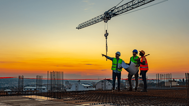 Construction workes on an unfinished commercial building at dusk.