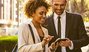 Image Real estate brokers review listing on a smart phone outside.