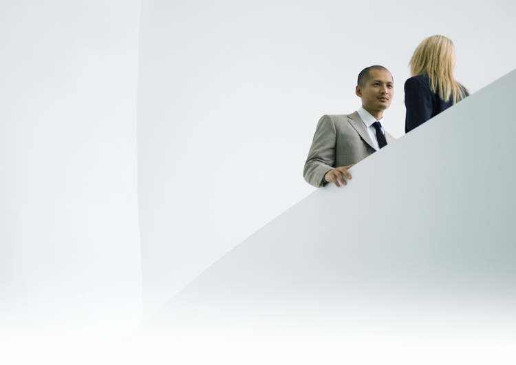 Man and woman business associates converse at the top of a stairwell