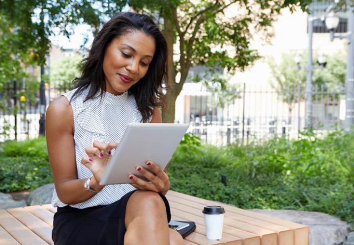 Businesswoman sitting on park bench reviewing documents.