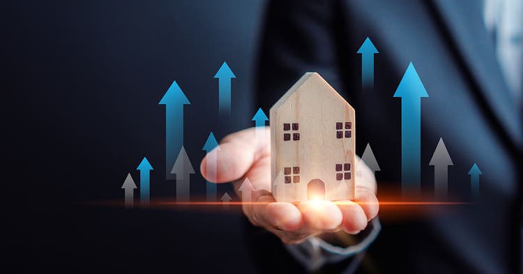 Businessman's palm holds house model surrounded by arrows pointing up