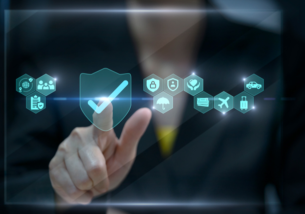 Businessperson in a suit taps a glowing shield with a checkmark, surrounded by cybersecurity, cloud, travel, health, and car icons.