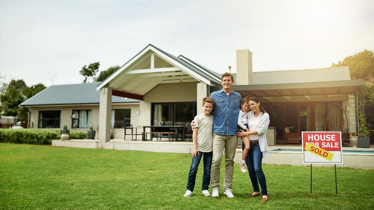 A family of four standing in front of their new home