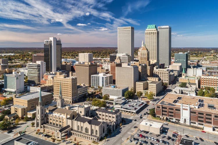 Aerial view of a downtown Tulsa Oklahoma featuring several tall, modern skyscrapers against a clear blue sky.