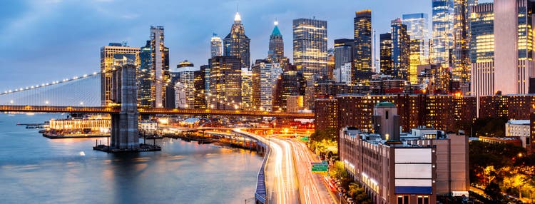 Brooklyn Bridge and East River of New York City illuminated at dusk