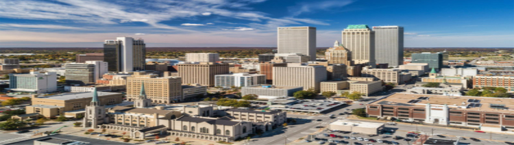 Aerial view of a downtown Tulsa Oklahoma featuring several tall, modern skyscrapers against a clear blue sky.